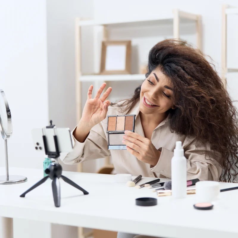 A woman sitting at a table with makeup on her face.